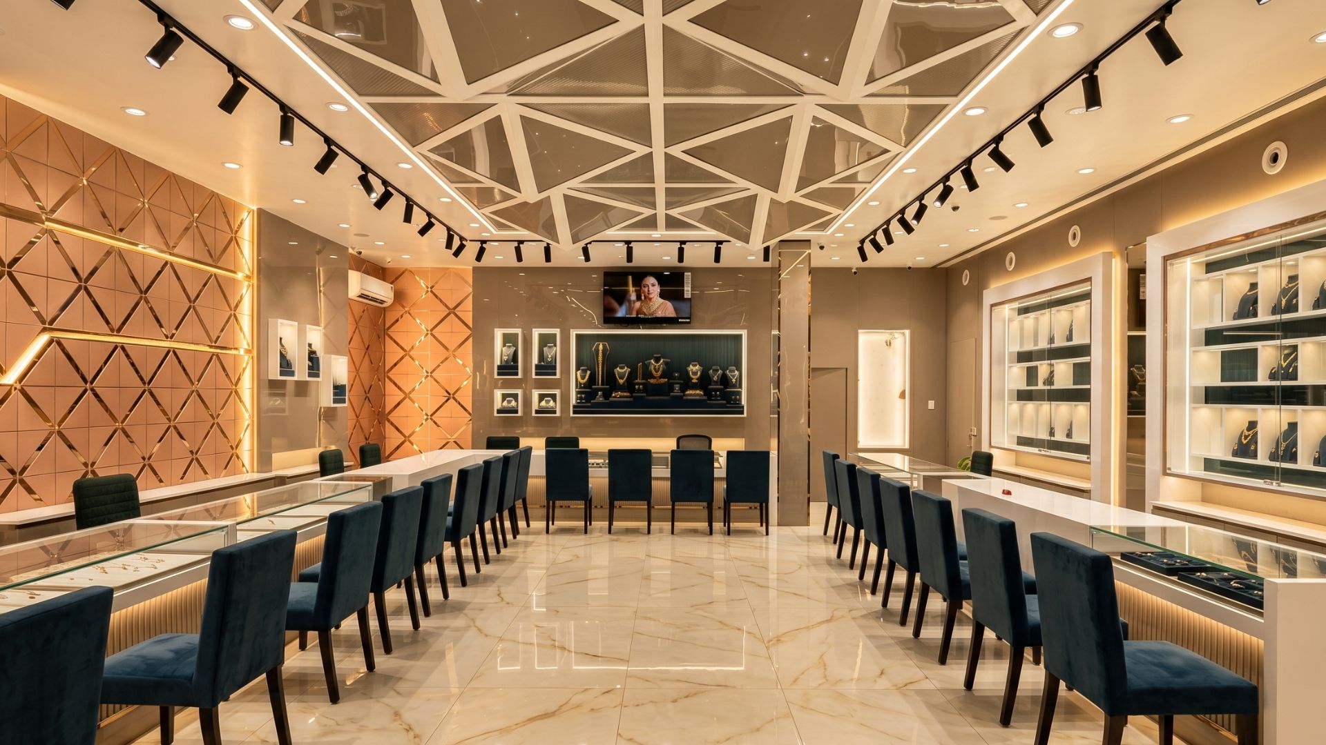Ultra-luxury Indian jewellery showroom interior with marble flooring, premium gold display counters, geometric ceiling lighting, and elegant seating designed for a high-end retail experience.